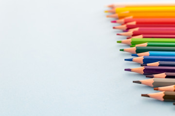 a set of colourful pencils lined up from dark to light focusing on the foreground 