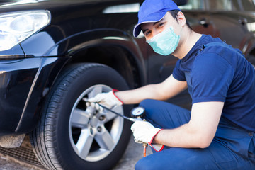 Masked mechanic inflating a tire