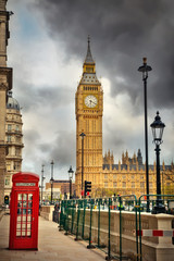 Fototapeta na wymiar Traditional red phone booth and Big Ben in London at cloudy day