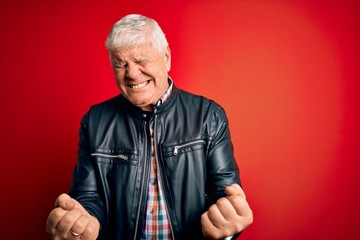 Senior handsome hoary man wearing casual shirt and jacket over isolated red background very happy and excited doing winner gesture with arms raised, smiling and screaming for success. Celebration