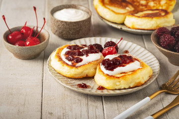 cottage cheese pancakes, tasty fritters curd with berries, sour cream and jam, close-up, copy space