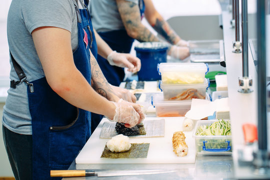 Sushi delivery. Masked and gloved chefs prepare sushi In the Restaurant's kitchen.