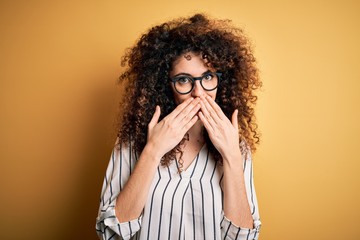 Young beautiful woman with curly hair and piercing wearing striped shirt and glasses laughing and...