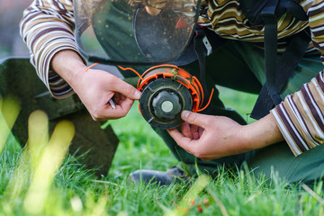 Close up on string trimmer head unknown caucasian man holding and repairing weed cutter replacing...