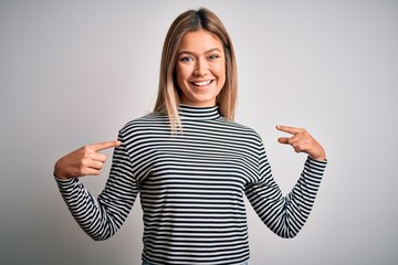 Young beautiful blonde woman wearing casual striped sweater over isolated background looking...