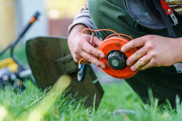 Close up on string trimmer head unknown caucasian man holding and repairing weed cutter replacing...