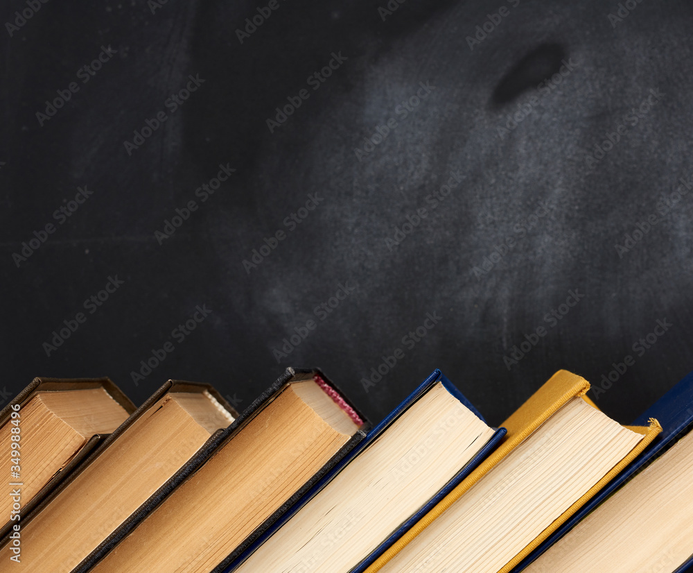 Poster stack of various books on the background of an empty black chalk board
