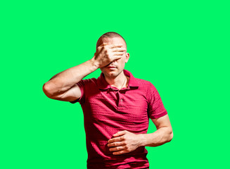 The man put  hand over his eyes against the green background