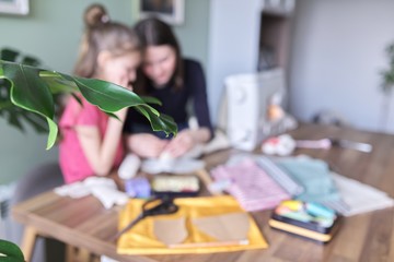 Children sitting at home, sewing doll, in defocus, background. Close-up of fabric, patterns, templates, scissors, threads, needles