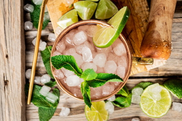 Cocktail de mojito en una taza de cobre y una pajita reutilizable, con ingredientes: lima, menta y hielo