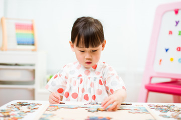 toddler girl playing wooden puzzle at home
