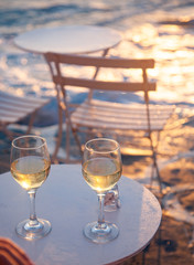 restaurant table by the sea with white wine at sunset summer holiday concept