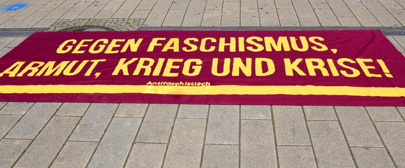 Auf der Straße liegendes Transparent gegen Faschismus, Armut, Krieg und Krise