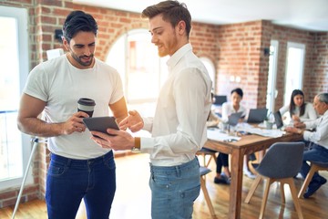Business workers smiling happy. Standing with smile on face working together using tablet at the office