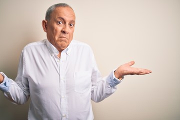 Fototapeta premium Senior handsome businessman wearing elegant shirt standing over isolated pink background clueless and confused expression with arms and hands raised. Doubt concept.