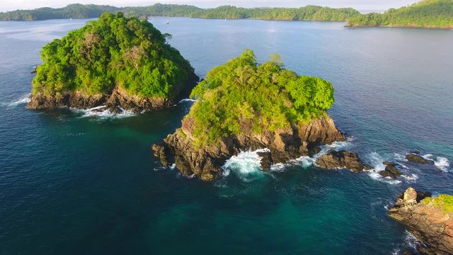 Hovering  Aerial View of Cavada Outter Islands (Isla Secas) Water Edge with Dense Jungle Trees, Waves Crashing on Rock Cliff Shore