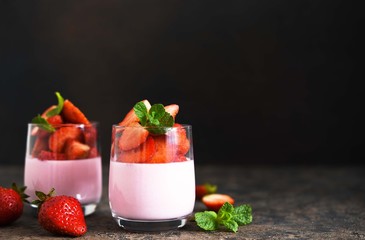 Pana cotta with strawberries and mint on a dark concrete background. Horizontal focus.