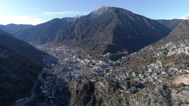 AERIAL DRONE APPROACH FROM THE MOUNTAINS TO ANDORRA CITY, WITH SNOWED PEAKS AND BEAUTIFUL AUTUMN VALLEY