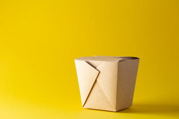 Eco friendly container for noodles from paper on yellow background. Plastic free. Top view. Space for text.