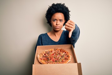 Young African American afro woman with curly hair holding delivery box with Italian pizza with...