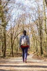 Obraz premium Sporty Spanish woman walking on the pathway in the forest in springtime, Garrotxa Volcanic Zone Natural Park