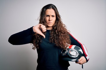 Beautiful motorcyclist woman with curly hair holding moto helmet over white background with angry...