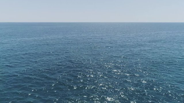 AERIAL DRONE SIDE VIEW OF EMPTY CALM BLUE SEA WITH BEAUTIFUL SUN REFLECTION IN THE SEA