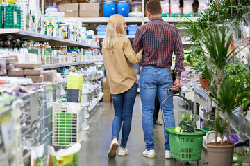 rear view on beautiful caucasian couple walking in the market, woman holding man's hand, shopping...