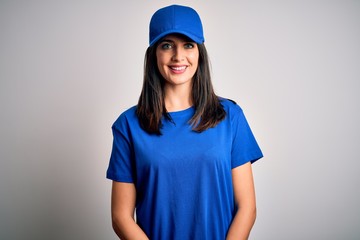 Young delivery woman with blue eyes wearing cap standing over blue background with a happy and cool smile on face. Lucky person.