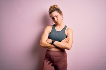 Young beautiful blonde sportswoman doing sport wearing sportswear over pink background skeptic and nervous, disapproving expression on face with crossed arms. Negative person.