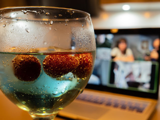 a gin and tonic with strawberries and blue tonic during a video call