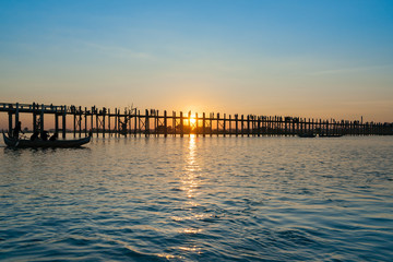 Fototapeta premium .U Bein Bridge crosses Taungthaman Lake near Amarapura in silhouette as sun sets behind