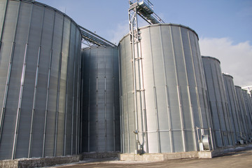 Construction of a feed mill agro-processing plant for processing and silos for drying cleaning and storage of agricultural products, flour, cereals and grain. Blues sky at the background.