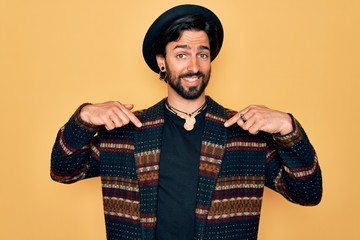 Young handsome hispanic bohemian man wearing hippie style and boho hat looking confident with smile...