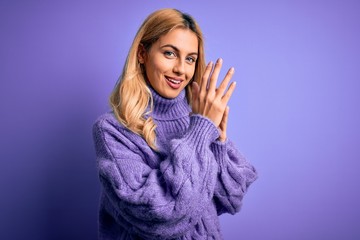 Young beautiful blonde woman wearing casual turtleneck sweater over purple background clapping and...