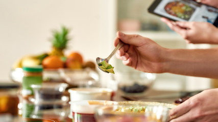 Close up of process of cooking. Man preparing meal while woman checking recipe using tablet. Vegetarians cooking in the kitchen together. Vegetarianism, healthy food, diet, stay home concept