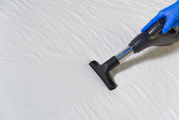 Vacuuming bed. Domestic home cleaning concept. Textile sofa chemical cleaning. Upholstered...