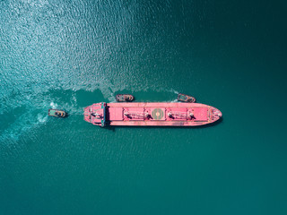 Aerial drone shoot the cargo ship enters the international trade sea port. The cargo ship sails...