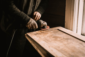 Polishing wood boards with a grinder in a workshop.