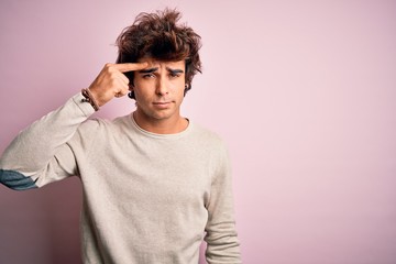 Young handsome man wearing casual t-shirt standing over isolated pink background pointing unhappy...