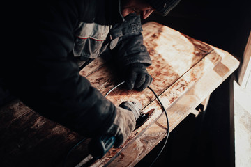 Polishing wood boards with a grinder in a workshop.