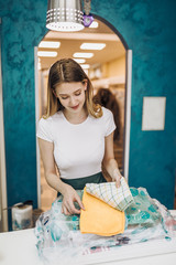 Young female worker in dry-cleaning salon.