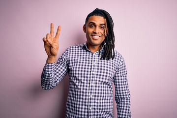 Young handsome african american afro man with dreadlocks wearing casual shirt smiling looking to the camera showing fingers doing victory sign. Number two.