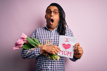 African american man with dreadlocks holding love mom message and tulips on mothers day scared in...