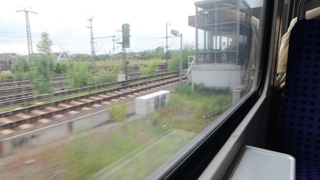 The view Through dirty Window of a moving commuter train entering station in Hamburg  on the fields sweeping outside the window