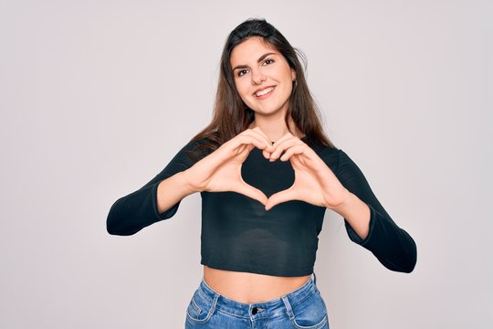Young beautiful brunette woman wearing casual sweater and jeans standing over isolated background smiling in love showing heart symbol and shape with hands. Romantic concept.