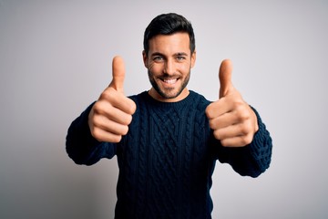 Young handsome man with beard wearing casual sweater standing over white background approving doing...