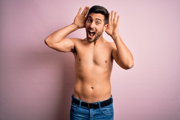 Young handsome strong man with beard shirtless standing over isolated pink background Smiling cheerful playing peek a boo with hands showing face. Surprised and exited