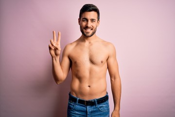 Young handsome strong man with beard shirtless standing over isolated pink background smiling looking to the camera showing fingers doing victory sign. Number two.