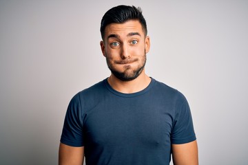 Young handsome man wearing casual t-shirt standing over isolated white background puffing cheeks with funny face. Mouth inflated with air, crazy expression.